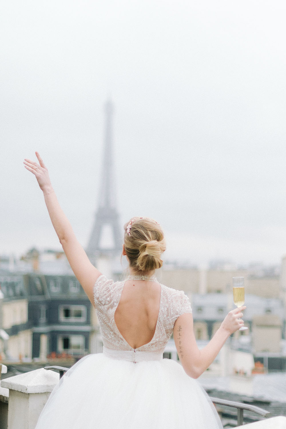 une mariée sur la terrasse de l ahotel marigan champs elysées bois une coupe de champagne